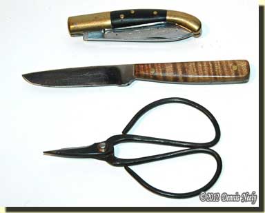 Top to bottom: A common reproduction folding knife, a neck knife and a pair of scissors.