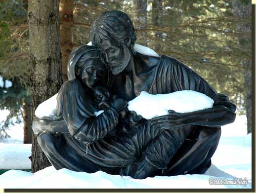 A sculture of the Holy Family covered with snow.
