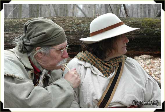 A traditional woodsman clucks on a single wing-bone call while his wife watches.