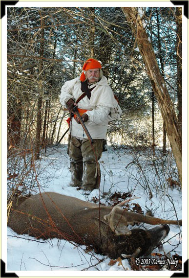 A traditional woodsman approaches a downed white-tailed buck.