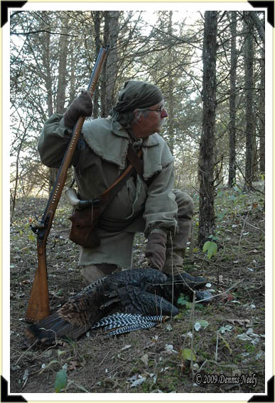 A traditional woodsman tends a downed turkey.