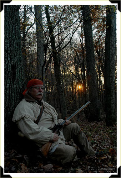 A traditional woodsman sitting with his back against an oak tree.