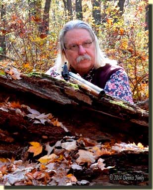 A traditional woodsman lurks behind an old oak trunk.