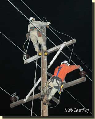 Two linemen climb a pole to begin replacing it.