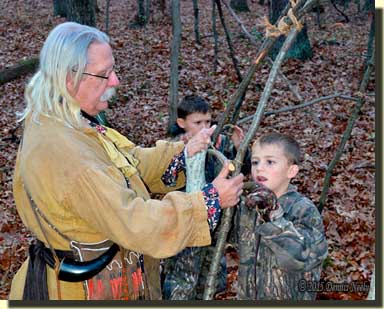 Two grandsons learn to lash saplings to the wigwam.