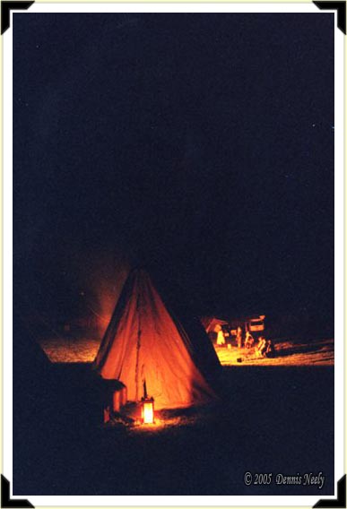 Candle light illuminates a wedge tent at night.