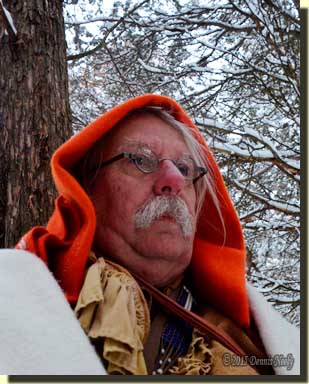 A traditional woodsman sitting against a cedar tree and looking downhill.