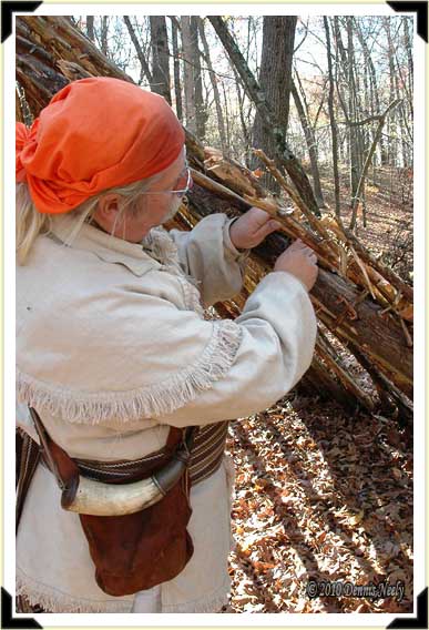 A trading post hunter lashes a rafter to a ridge beam for a fall hunting camp.