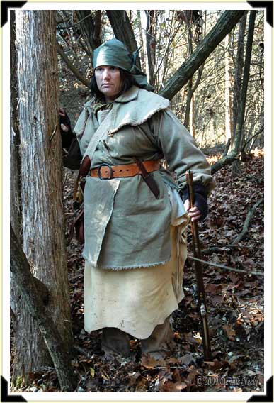 A traditional hunter pauses beside a red cedar tree.