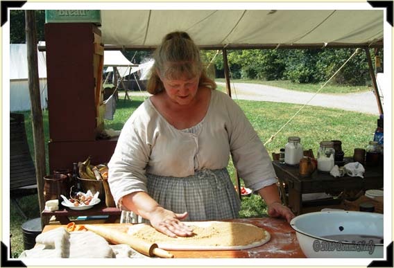 An 18th-century woman spreads sugar on rolled out dough.