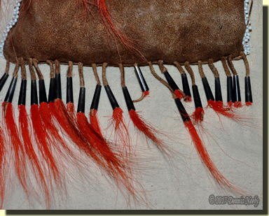 The worn deer-hair cones on the bottom of Msko-waagosh's shot pouch.